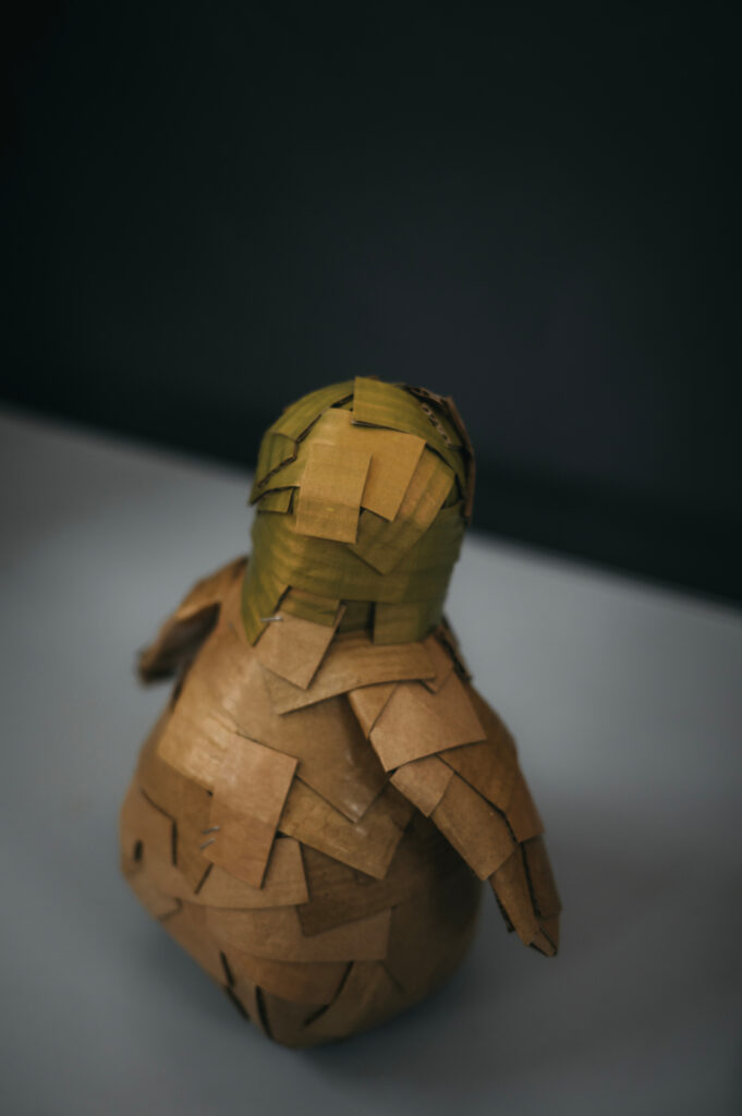 Detalle cabeza pingüino verde tornasol. Escultura de cartón. Orgaz.
