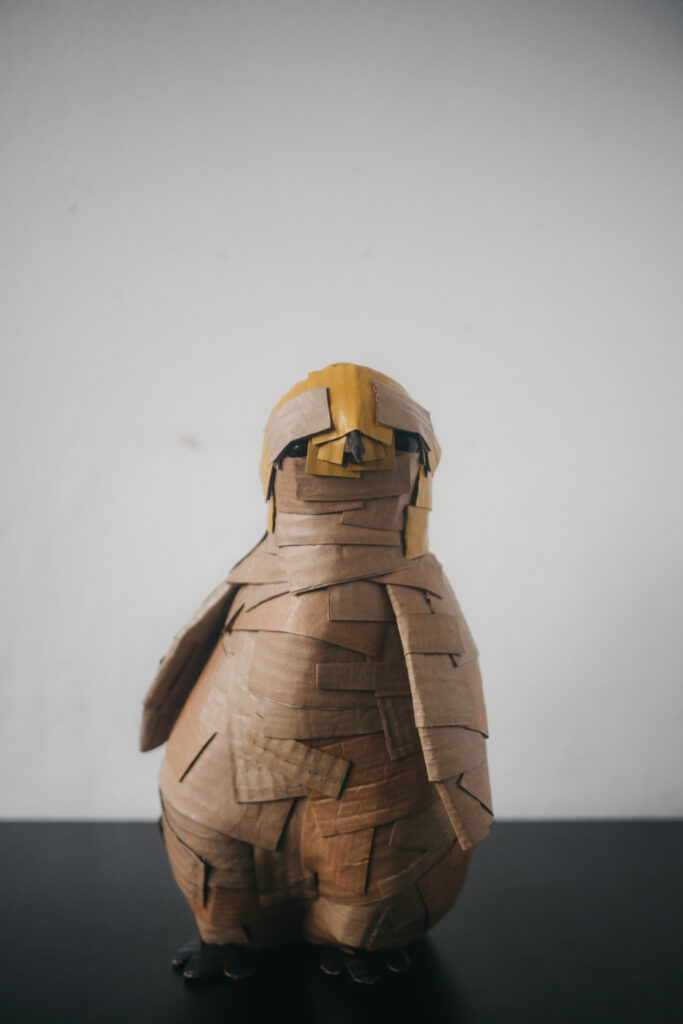 Pingüino amarillo de frente. Escultura de cartón. Orgaz.