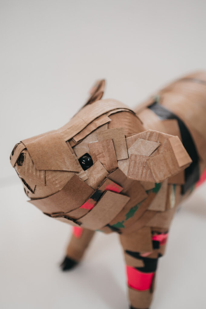 Cerdito en rosa de perfil, primer plano. Escultura de cartón. Orgaz