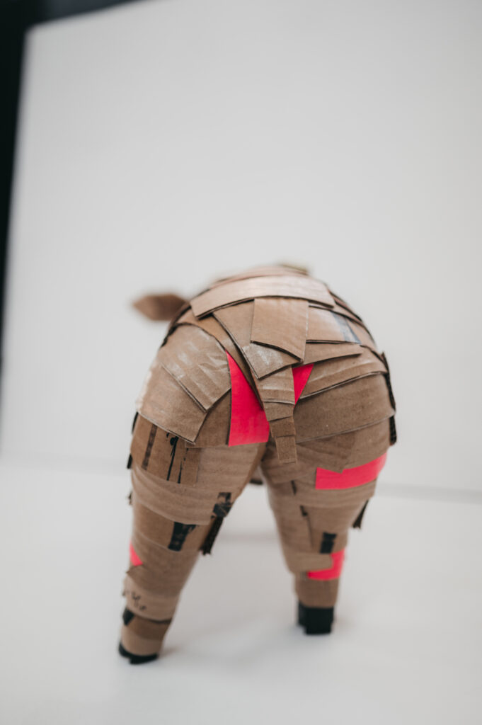 Vista trasera del cerdito rosa con rabito. Escultura de cartón. Orgaz