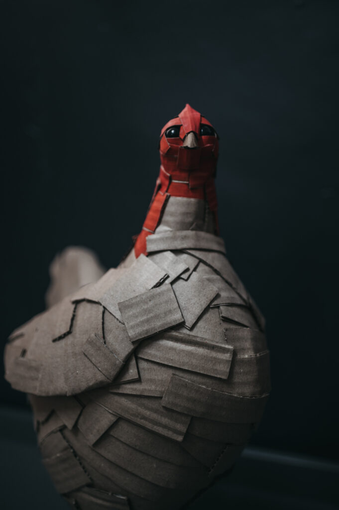 Detalle de la gallina roja. Escultura de cartón. Orgaz