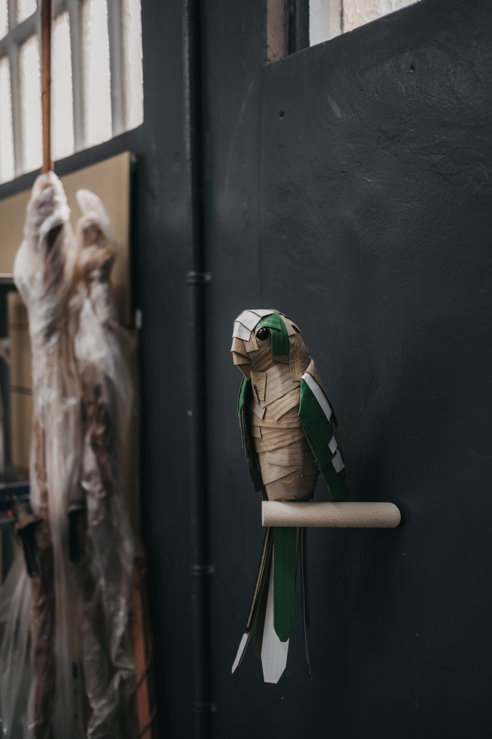 Guacamayo en verde y blanco de frente. Escultura de cartón. Orgaz
