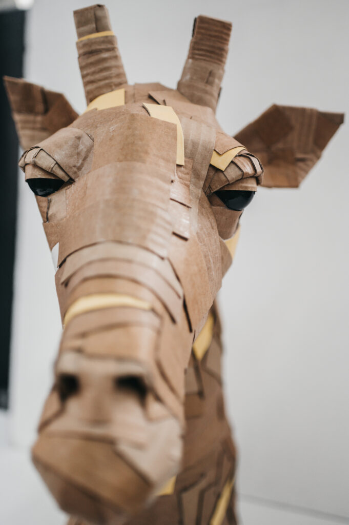 Jirafa amarilla de frente. Escultura de cartón. Orgaz