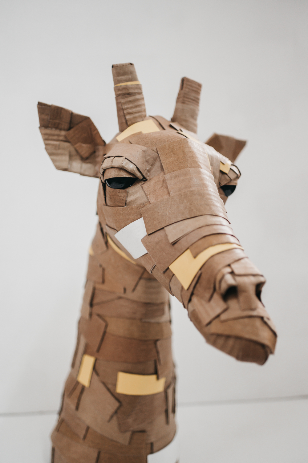 Jirafa amarilla de perfil. Escultura de cartón. Orgaz