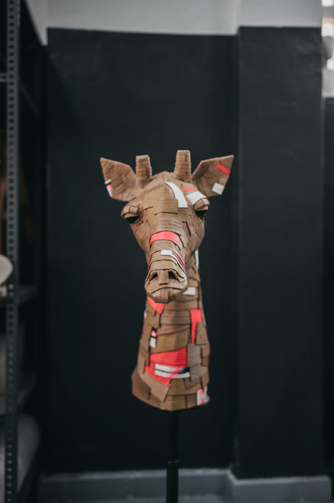Jirafa rosa y graf de frente, busto entero. Escultura de cartón. Orgaz
