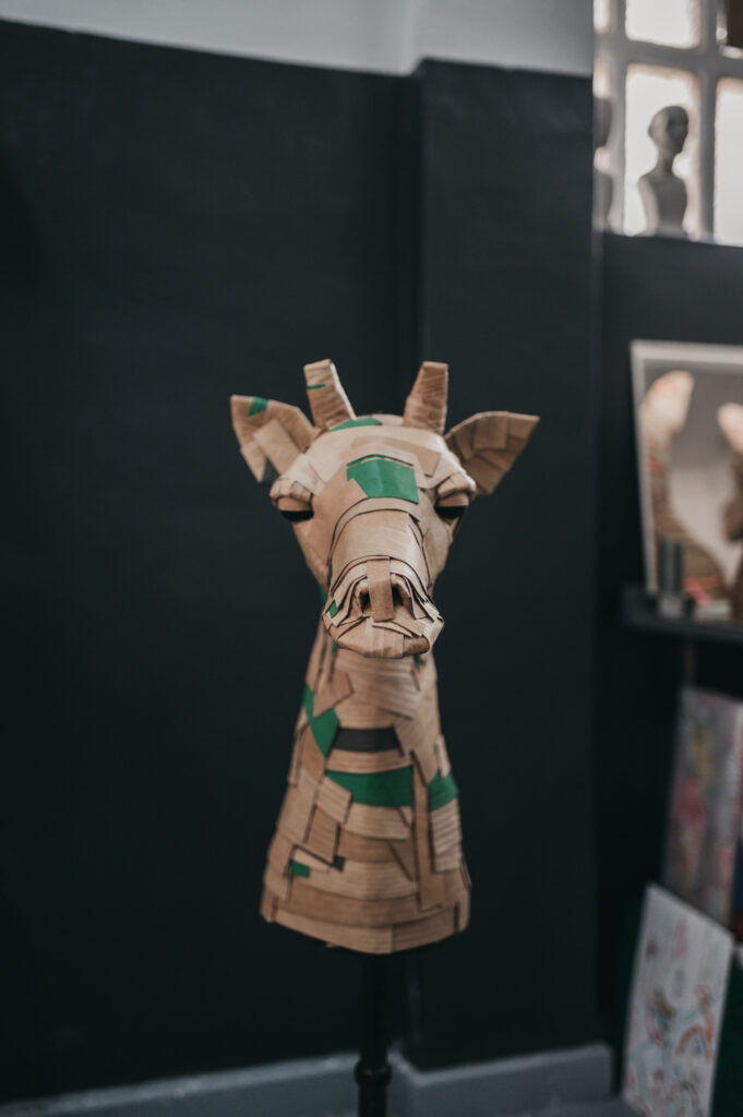 Jirafa verde kelly de frente, cuerpo entero. Escultura de cartón. Orgaz